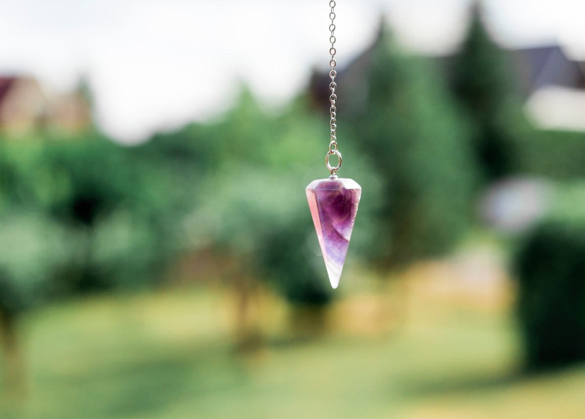 Amethyst crystal quartz pendulum hanging on chain.